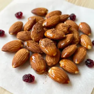 To make Maple Cinnamon Roasted Almonds, gather these simple ingredients: - 2 cups raw almonds - 1/4 cup pure maple syrup - 1 tablespoon ground cinnamon - 1/4 teaspoon salt - 1/2 teaspoon vanilla extract - 1 tablespoon coconut oil (or olive oil) These ingredients create a sweet and warm flavor that you will love. To make your roasted almonds even more exciting, try adding: - 1/4 cup dried cranberries or raisins for extra sweetness - A pinch of nutmeg for a warm spice that complements cinnamon These options let you customize your snack to suit your taste. For the best flavor, choose high-quality ingredients. Look for: - Raw almonds from a trusted store or farmer's market - Pure maple syrup, not imitation syrup, for a rich taste - Fresh ground cinnamon to ensure full flavor Shopping at local markets helps you find the freshest options. {{ingredient_image_1}} Start by preheating your oven to 350&deg;F (175&deg;C). This step is key for even roasting. Next, grab a baking sheet and line it with parchment paper. The parchment helps prevent sticking and makes cleanup easy. You want a clean surface where the almonds can roast freely. In a mixing bowl, add these ingredients: - 1/4 cup pure maple syrup - 1 tablespoon ground cinnamon - 1/4 teaspoon salt - 1/2 teaspoon vanilla extract - 1 tablespoon coconut oil (or olive oil) Whisk them together until they blend into a smooth mixture. The maple syrup will give sweetness, while the cinnamon adds warmth. The salt enhances the flavors. This blend coats the almonds well, making them tasty. Now, add 2 cups of raw almonds to your bowl. Stir them until they are fully coated with the maple-cinnamon mixture. This step ensures every almond gets flavor. Then, spread the coated almonds in a single layer on the lined baking sheet. Make sure they are not too crowded. This will help them roast evenly. Place the baking sheet in your preheated oven. Roast for about 15-20 minutes. Remember to stir the almonds halfway through. This helps them brown nicely. Watch them closely to avoid burning. You want them golden brown and fragrant. Once done, take them out and let them cool on the baking sheet. The almonds will harden as they cool. If you like, toss in 1/4 cup of dried cranberries or raisins for added sweetness after cooling. Once cool, store the almonds in an airtight container. Enjoy your tasty snack! To get the best flavor, use pure maple syrup. It adds a rich, sweet taste. Ground cinnamon is key too; it gives warmth and spice. Make sure to mix your ingredients well. This helps each almond get coated evenly. If you want extra sweetness, add dried cranberries or raisins. They pair great with the maple and cinnamon. To prevent burning, check your almonds often while roasting. Stir them halfway through to keep them from browning too much. Use a timer for 15 minutes, but watch closely after that. If they smell nutty, they are close to done. You want them golden brown, not dark brown. For freshness, store your roasted almonds in an airtight container. This keeps them crunchy and tasty. Make sure they are completely cool before you store them. If left at room temperature, they last about a week. For longer storage, keep them in the fridge. They can last up to a month that way. Pro Tips Watch the Oven: Keep a close eye on the almonds as they roast. They can go from perfectly golden to burnt in just a minute or two. Experiment with Flavors: Feel free to add other spices like nutmeg or ginger for a unique twist on the flavor profile. Storage Matters: Store the cooled almonds in an airtight container at room temperature to keep them fresh and crunchy. Perfect Pairing: These roasted almonds make a great snack on their own or can be added to salads and yogurt for extra crunch and flavor. {{image_2}} You can switch up the sweeteners in this recipe. If you want less sugar, try using honey or agave syrup. Both can bring a nice flavor twist. You might also like to use brown sugar for a deeper taste. For spices, consider using nutmeg or ginger. Each spice adds a new layer of warmth. You can mix and match these options to find your favorite blend. Feel free to add other nuts or seeds to this recipe. Cashews or pecans pair well with almonds. They offer different textures and flavors. You can also try seeds like pumpkin or sunflower seeds. They add crunch and healthy fats. When adding, keep the total amount the same. This helps the coating stick well. Mix the nuts and seeds in the same bowl before roasting. Roasted almonds are great on their own, but you can use them in many ways. Try adding them to salads for a crunchy bite. They work well in granola or trail mix too. You can also sprinkle them on yogurt for extra taste. Another fun idea is to use them in baking. Chop them and add to cookies or muffins. They can even be a topping for ice cream. The options are endless, so get creative! Maple cinnamon roasted almonds are not only tasty but also packed with nutrition. A typical serving of these almonds (about 1 ounce or 28 grams) contains: - Calories: Approximately 170 - Protein: 6 grams - Fat: 15 grams - Carbohydrates: 8 grams - Fiber: 3 grams These numbers can vary based on the exact amounts of maple syrup and any added fruits. The almonds provide healthy fats, protein, and fiber, making them a smart snack choice. Almonds are a nutrient-rich food with several health benefits: - Heart health: Almonds can help lower bad cholesterol levels. They may lower the risk of heart disease. - Weight management: Eating almonds in moderation can help with weight control. - Nutrient density: They are high in vitamin E, magnesium, and antioxidants. Maple syrup also has its perks: - Natural sweetener: It is a better alternative to refined sugars. - Rich in minerals: Maple syrup contains zinc, manganese, and calcium. - Antioxidants: It offers antioxidants that can help reduce inflammation. Combining almonds with maple syrup creates a snack that is both delicious and good for you. To enjoy maple cinnamon roasted almonds as a balanced snack, consider these ideas: - Pair them with Greek yogurt for protein and creaminess. - Mix them into oatmeal for added texture and flavor. - Serve with apple slices for a sweet and crunchy combo. These options can enhance the snack's nutritional value and keep you full longer. Enjoy your healthy treat! Yes, you can use other nuts. Try walnuts, pecans, or cashews. Each nut brings a unique flavor. You may need to adjust the roasting time. Walnuts may roast faster, while pecans may take a bit longer. Always watch them closely to avoid burning. The almonds are done when they turn golden brown and smell nice. They usually take about 15 to 20 minutes in the oven. Stir them halfway to ensure even cooking. If they look dark or smell burnt, they are overdone. Always trust your senses! Leftover roasted almonds are great for snacks or toppings. You can add them to salads or yogurt. They also make a tasty addition to oatmeal. Store them in an airtight container to keep them fresh. Enjoy them as a quick snack anytime! This guide covered everything you need for delicious roasted almonds. You learned the best ingredients and how to prepare them. We walked through simple steps for roasting and shared tips to enhance flavor and freshness. The variations offered creative ideas, while the nutritional section highlighted their health benefits. Remember, choose quality ingredients for the best taste. Enjoy your roasted almonds as a snack or in recipes. Combining knowledge and practice will lead to tasty results every time.