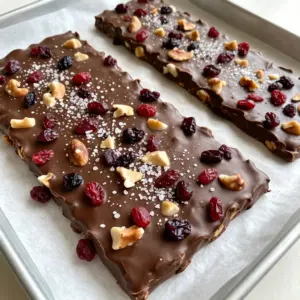 - 12 oz dark chocolate (70% cocoa or higher), chopped - 1 cup mixed nuts (almonds, walnuts, pecans), roughly chopped - 1/2 cup dried cranberries or cherries - 1/4 cup unsweetened coconut flakes - 1 teaspoon flaky sea salt (plus extra for sprinkling) Dark chocolate is the star of this treat. It has rich flavor and pairs well with nuts and fruit. Choose chocolate that is at least 70% cocoa for the best taste. Mixed nuts add crunch and healthy fats. You can use almonds, walnuts, or pecans based on your liking. Dried fruits like cranberries or cherries add a sweet touch. They balance the chocolate's bitterness. Coconut flakes give a tropical feel and nice texture. Finally, flaky sea salt enhances the flavor. It makes every bite a delight. - Microwave-Safe Bowl - Baking Sheet - Parchment Paper - Spatula To make this bark, you need a few simple tools. A microwave-safe bowl is best for melting the chocolate. Use a baking sheet to pour the mixture onto. Parchment paper helps with easy removal and cleanup. A spatula is great for spreading the chocolate evenly. With these items, you are ready to create your delicious Dark Chocolate Sea Salt Bark! {{ingredient_image_1}} - Line Baking Sheet with Parchment Paper Start by taking a baking sheet and lining it with parchment paper. This step makes it easy to lift the bark after it sets. It also helps with clean-up, saving you time and effort. - Melt Dark Chocolate Next, chop 12 ounces of dark chocolate. Place it in a microwave-safe bowl. Heat the chocolate in the microwave using 30-second bursts. Stir it each time you check to ensure it melts evenly. You want it smooth and glossy. - Mix in Nuts, Dried Fruits, and Coconut Once your chocolate is melted, grab your mixed nuts, dried cranberries, and coconut flakes. Add these to the chocolate. Stir quickly to mix everything well. You want each piece coated in that yummy chocolate. - Pour, Spread, and Sprinkle Sea Salt Carefully pour the chocolate mixture onto your lined baking sheet. Use a spatula to spread it out evenly. Aim for about a quarter-inch thick layer. While the chocolate is still warm, take your flaky sea salt and sprinkle it over the top. Add a little more if you like a stronger flavor. - Chill and Break into Pieces Now, place the baking sheet in the fridge. Let it chill for about 1 to 2 hours. This step helps the chocolate set properly. Once it's firm, lift the bark from the parchment. Break it into pieces of your desired size. Enjoy your dark chocolate sea salt bark! - Use a microwave-safe bowl to melt your chocolate. You can also use a double boiler. Both methods work well. - Heat the chocolate in 30-second bursts. After each time, stir it well. This helps it melt evenly and prevents burning. - Choose nut varieties that you love. Almonds, walnuts, and pecans all add nice crunch. - If you like more salt, sprinkle extra sea salt on top. This enhances the sweet and salty taste. - For a beautiful presentation, serve the bark on a decorative plate. - Add a small dish of sea salt for those who want more. Pair it with fruit or a glass of milk for a fun snack! Pro Tips Use High-Quality Chocolate: The better the chocolate, the better your bark will taste. Opt for chocolate with at least 70% cocoa for rich flavor. Customize Your Mix-Ins: Feel free to experiment with different nuts, dried fruits, or even spices to create your own unique flavor combinations. Watch the Melting Process: Be careful not to overheat the chocolate. Stirring frequently helps it melt evenly and prevents burning. Perfect Breaks: To achieve clean breaks, score the chocolate with a knife before it fully hardens, making it easier to snap into pieces later. {{image_2}} You can switch up the dried fruits to make this treat your own. Try using: - Dried apricots - Dried figs - Raisins Each fruit adds a unique flavor. Dried apricots give a sweet touch. Figs add a chewy texture. Raisins bring a classic taste. Instead of nuts, you can use seeds. Sunflower seeds or pumpkin seeds work well. They add crunch and are great for nut-free diets. Seeds also offer a nice pop of color. You don't have to stick to dark chocolate. Milk chocolate can make it sweeter. White chocolate offers a creamy taste. Both will pair nicely with sea salt. If you need sugar-free options, look for sugar-free dark chocolate. Dairy-free chocolate is also available. These options are perfect for those with dietary needs. Want to spice things up? Consider adding a dash of cinnamon. It brings warmth and a cozy feel. You could also try chili powder for a kick. Just a pinch will do! Extracts can enhance the flavor too. Vanilla extract adds sweetness and depth. Mint extract gives a fresh taste. A few drops can completely change your bark. Think about these variations as you create your dark chocolate sea salt bark. Each change brings a new experience and flavor. To keep your dark chocolate sea salt bark fresh, store it in an airtight container. This helps shield it from air and moisture. Use a container that fits the bark snugly to avoid excess movement. You can keep it at room temperature for best flavor. However, if you live in a warm area, refrigeration is wise. Just remember, cold storage can make the bark firmer. Your dark chocolate sea salt bark can last about two weeks at room temperature. For the best taste, eat it within the first week. Look for signs of spoilage. If you see white spots or a dull surface, this could mean the chocolate has gone bad. It may still be safe to eat, but the taste might not be as good. If you have leftovers, get creative! You can chop the bark into small pieces and mix it into yogurt or oatmeal for extra crunch. You can also use it in a snack mix. Combine the bark pieces with popcorn, pretzels, and nuts for a sweet and salty treat. This way, no piece goes to waste, and you get to enjoy it in new ways! Dark chocolate sea salt bark is a tasty treat made from rich dark chocolate, nuts, dried fruits, and coconut. The key ingredients are: - 12 oz dark chocolate (70% cocoa or higher), chopped - 1 cup mixed nuts (almonds, walnuts, pecans), roughly chopped - 1/2 cup dried cranberries or cherries - 1/4 cup unsweetened coconut flakes - 1 teaspoon flaky sea salt (plus extra for sprinkling) This bark combines sweet and salty flavors. It melts in your mouth and gives a satisfying crunch. Making dark chocolate sea salt bark is simple. Here&rsquo;s a quick summary of the steps: 1. Prep Baking Sheet: Line it with parchment paper. 2. Melt Chocolate: Heat in intervals until smooth. 3. Mix Add-ins: Stir in nuts, dried fruits, and coconut. 4. Pour and Spread: Pour the mixture onto the sheet. 5. Sprinkle Salt: Add flaky sea salt while warm. 6. Chill: Refrigerate until set, about 1-2 hours. 7. Break into Pieces: Once hardened, break into your desired size. Yes, you can customize your bark. Feel free to swap in your favorite nuts or dried fruits. Some tasty options include: - Cashews or hazelnuts instead of almonds - Raisins or apricots instead of cranberries Mixing different flavors keeps it fresh and exciting! Dark chocolate has health benefits when eaten in moderation. It contains antioxidants that can help improve heart health. Some benefits include: - Lowering blood pressure - Improving blood flow - Reducing inflammation Choose chocolate with at least 70% cocoa for the best benefits. Yes, you can freeze this bark. To freeze, wrap it tightly in plastic wrap or foil. Place it in an airtight container. When you want to enjoy it, let it thaw in the fridge. This keeps the texture nice and smooth. Enjoy your treat later! Dark Chocolate Sea Salt Bark is simple and fun to make. We covered ingredients like dark chocolate, nuts, and dried fruits. You learned about the tools you need and clear steps to prepare it. Customizing flavors and storing leftovers brings joy to your kitchen. In the end, making chocolate bark opens up endless possibilities. Enjoy creating tasty treats that fit your taste. You have the knowledge now, so get started!